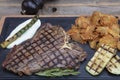 Barbecued t-bone steak seasoned with fresh herbs and marinade served with a cutting board in a steakhouse. Delicious restaurant