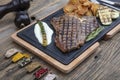 Barbecued t-bone steak seasoned with fresh herbs and marinade served with a cutting board in a steakhouse. Delicious restaurant