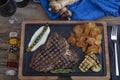 Barbecued t-bone steak seasoned with fresh herbs and marinade served with a cutting board in a steakhouse. Delicious restaurant Royalty Free Stock Photo