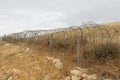 Barbed tape or razor wire fence across the desert hill on cloudy day Royalty Free Stock Photo