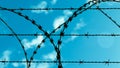 Barbed wire against blue sky and clouds Royalty Free Stock Photo