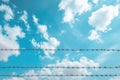 Barbed wire against a blue sky with clouds Royalty Free Stock Photo