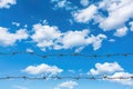 Barbed wire against blue sky with clouds Royalty Free Stock Photo
