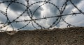 Barbed Wire Against a Dramatic Cloudy Sky and Concrete Wall fence security Royalty Free Stock Photo