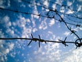 Barbed wire against the sky with clouds Royalty Free Stock Photo