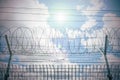 Barbed wire against sky with sun, barbed wire bottom view and morning sun, Barbed wire fence and wire mesh with sky background Royalty Free Stock Photo