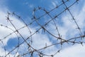 Barbed wire on the background of a blue sky with clouds. Royalty Free Stock Photo