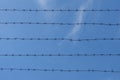 Barbed wire on the background of a blue sky with clouds. Royalty Free Stock Photo