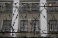 Barbed wire barrier with beautiful sky clouds and brick building behind the scene. Royalty Free Stock Photo