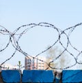 Barbed wire on a blurred background of a fragment of residential buildings. Concept of isolation. Selective focus