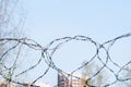 Barbed wire on a blurred background of a fragment of residential buildings. Concept of isolation. Selective focus