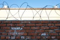 Barbed wire with brick wall and light building in the background against the blue sky Royalty Free Stock Photo