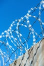 Barbed wire extends along the top of a sturdy concrete fence wall for heightened security measures