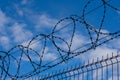 Barbed wire fence on background with blue sky and white clouds. Concept of freedom Royalty Free Stock Photo