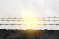 Barbed wire on fence, cloudy sky, black and white, sun Royalty Free Stock Photo