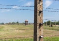 Barbed wire fence with the out of focus watch tower in the background in concentration camp Auschwitz II - Birkenau. Royalty Free Stock Photo