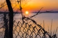 Barbed wire fence over background of beautiful sunset on lake Royalty Free Stock Photo