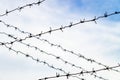 Barbed wire in the foreground and background against a background of blue sky and blue clouds. Royalty Free Stock Photo