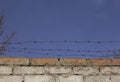 Barbed wire over old brick wall against the sky. Royalty Free Stock Photo