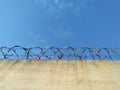 Barbed wire prison wall with blue sky background Royalty Free Stock Photo