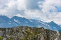 Barbed wire separating the mountain landscape. In the foreground there are solid stones and mountain plants, flowers Royalty Free Stock Photo
