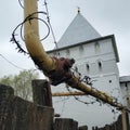 Barbed wire stretched over a yellow pipe. Behind her is a church. Old white brick church. Royalty Free Stock Photo