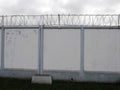 Barbed wire on white fence. Concrete wall, on the background barbed wire, prison concept, space for text