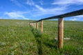 Barbed Wire and Wooden Fence Cuts Across Green Field Royalty Free Stock Photo