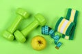 Barbells, apple and measure tape near green hand band Royalty Free Stock Photo