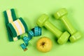 Barbells, apple and measure tape near green hand band Royalty Free Stock Photo