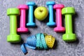 Barbells, colorful tape measures and apple placed in pattern, topview
