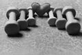 Barbells in different colors and heart placed in pattern, closeup