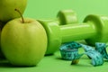 Barbells near juicy green apple. Dumbbells in bright green color Royalty Free Stock Photo