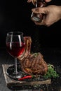 barbeque steak and red wine. Milled spices falling from pepper mill on grilled pieces of beef steak