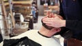 Barber applying beard styler to male face