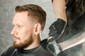 The barber cleans the neck of an adult man with a brush with talc after a haircut on a white brick wall background Royalty Free Stock Photo