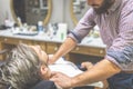 Barber covering client with towel before giving him a shave at barbershop