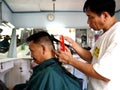 A barber cuts the hair of his customer inside his barbershop