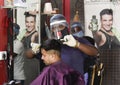 Barber cuts hair wearing protective shield