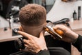 Barber cuts red-haired client with trimmer in barbershop