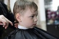 Barber cutting hair of a serious kid Royalty Free Stock Photo