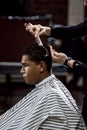 The barber is cutting a man`s hair holding scissors and comb in his hands opposite the mirror in a barbershop Royalty Free Stock Photo