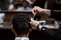 The barber is cutting a man`s hair holding scissors and comb in his hands opposite the mirror in a barbershop Royalty Free Stock Photo