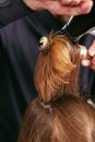 Barber dries the hair with the hair dryer of young, beautiful girl in a beauty salon