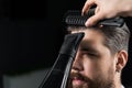 Barber dries the hair of a handsome bearded man after a fashionable haircut. The work of a hairdresser during the
