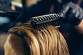 Barber drying male hair in hairdressing salon.