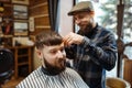 Barber in hat cuts the client `s hair, barbershop