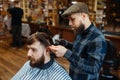 Barber holds comb and cuts the client `s hair