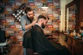 Barber makes hairstyle of client man by clipper