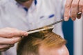 Barber Making Haircut Bearded Man In Barbershop. Professional stylist cutting client hair in salon. Barber using Royalty Free Stock Photo